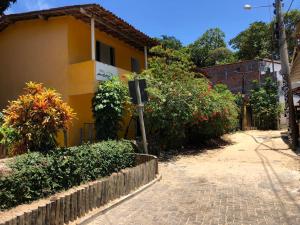 una calle con un edificio amarillo y algunos arbustos en Pousada e Camping América, en Morro de São Paulo