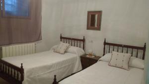 Un dormitorio con dos camas y un espejo en la pared. en Casa Fraile, en Olmedilla del Campo