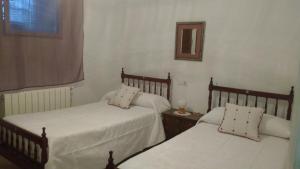 a bedroom with two beds and a mirror on the wall at Casa Fraile in Olmedilla del Campo