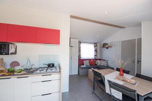 a kitchen and living room with red cabinets and a table at Camping de Kergo in Ploemel