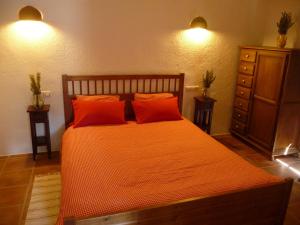 a bedroom with an orange bed with two orange pillows at Casas Rurales Cortijo Leontino in Taberno