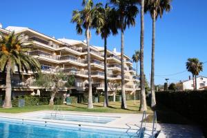 een groot gebouw met palmbomen en een zwembad bij Apartamento Bahia Dorada in Cambrils