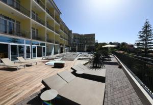 a courtyard of a building with benches and an umbrella at Hotel Do Campo in Ribeira Brava