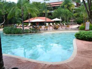 a swimming pool with chairs and umbrellas in a resort at Hotel Luupi apto 234 - Rio Quente Go in Rio Quente