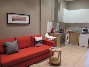 埃納雷斯堡的住宿－La Casa Tahona Plaza de Cervantes，一间带红色沙发的客厅和一间厨房