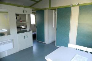 a kitchen with white cabinets and green walls at Camping la Croix du Sud in Saint-Tropez