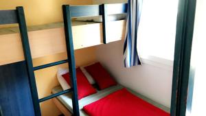 a bedroom with two bunk beds with red pillows at Camping la Croix du Sud in Saint-Tropez