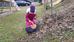 Ein kleines Mädchen spielt mit einem Korb im Gras in der Unterkunft Hirmhof in Reinsberg