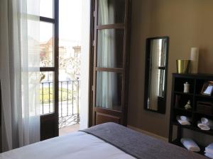 Un dormitorio con una cama y una ventana con balcón. en La Casa Tahona Plaza de Cervantes, en Alcalá de Henares