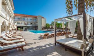 a hotel patio with lounge chairs and a swimming pool at Natalie Hotel in Laganas
