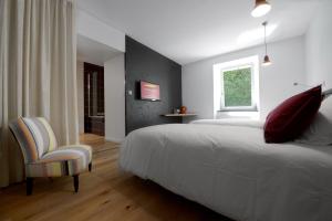 a bedroom with a bed and a chair and a window at La Bonne Auberge in Clerval