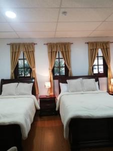 Quinta Spa El Rosal في أمباتو: سريرين في غرفة بها نافذتين