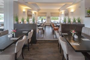 a dining room with tables and chairs and plants at Beach Hotel California in Kalifornien