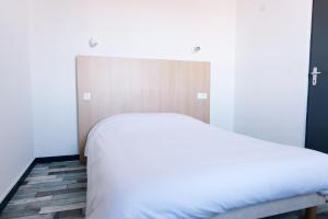 1 dormitorio con cama blanca y cabecero de madera en Welcomotel Limoges, en Limoges