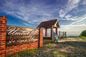 a sign on a brick wall next to the beach at Umbut Bayu in Dungun