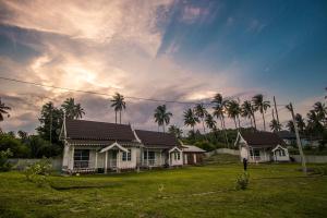 a house with palm trees in front of a yard at Umbut Bayu in Dungun