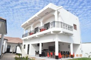 un edificio blanco con balcón y sillas en Sukuta Nema Guest House, en Banjul