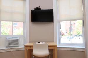 a room with a desk with a television and two windows at Stylish Downtown Studio in the South End, C. Ave #1 in Boston