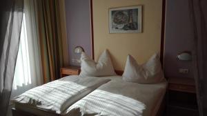 um quarto com uma cama com lençóis brancos e almofadas em Pension Restaurant Meran em Abtenau