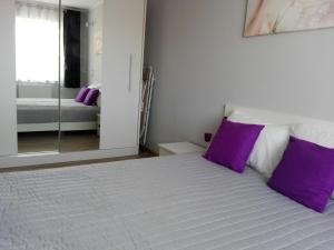 una camera da letto con letto, cuscini viola e specchio di Apartament Marzenie 6 - Opole a Opole