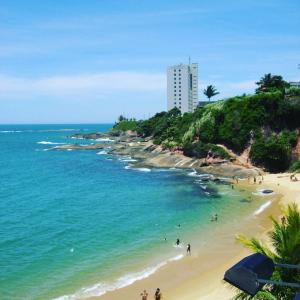 a beach with people in the water and a building at Guarapari ES apartamento frente para o mar in Guarapari