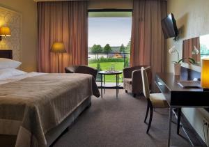 トラカイにあるMargis Hotel & SPAのベッド、デスク、窓が備わるホテルルームです。