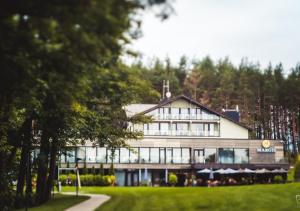 a large building with trees in front of it at Margis Hotel & SPA in Trakai