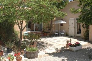 a house with a patio with potted plants and an umbrella at Le Termenès in Félines-Termenès