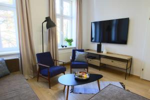 uma sala de estar com uma televisão e duas cadeiras e uma mesa em Apartament Grodzka 4 em Bydgoszcz