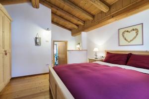 a bedroom with a large bed with a purple blanket at Maso Vaia in Cavalese