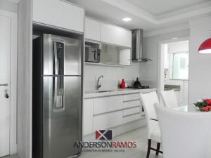 una cocina con nevera de acero inoxidable y armarios blancos en 1057 - Apartamento para locação em Bombinhas, en Bombinhas