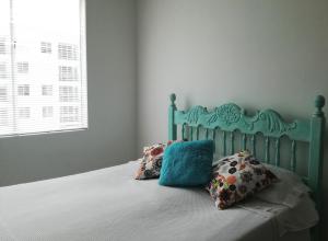 1 cama con cabecero azul y 2 almohadas en Depto Condominio Aqualina, en Girardot