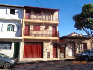 um edifício com portas vermelhas e varandas numa rua em Pousada Bela Vista em São Tomé das Letras