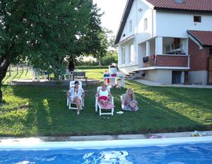 3 Personen sitzen auf Gartenstühlen am Pool in der Unterkunft Teo-Sport in Cerovac