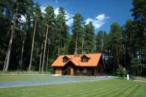 a house with an orange roof in the middle of a field at Dom pod Sosnami in Płaska