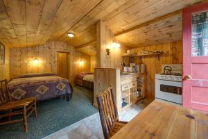 a log cabin bedroom with a bed and a kitchen at Silver Gate Lodging in Cooke City