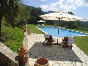 a swimming pool with two chairs and an umbrella at Can Serola in Sales del Llierca