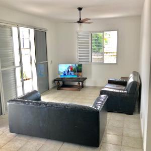 a living room with two leather couches and a flat screen tv at CASA COM 3 QUARTOS NA PRAIA DE CAIOBA in Matinhos