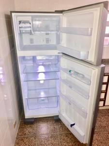 an empty refrigerator with its door open in a kitchen at CASA COM 3 QUARTOS NA PRAIA DE CAIOBA in Matinhos