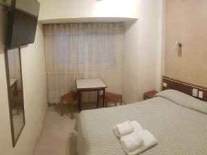 a small bedroom with a bed and a table at Hotel Compostela in Mar del Plata