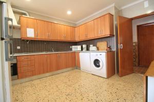 eine Küche mit Holzschränken, einer Waschmaschine und einem Trockner in der Unterkunft Casa da Amoreira in Luz de Tavira