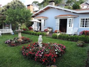 a white dog statue in a garden in front of a house at Refugio Fofo - casa de temporada in Campos do Jordão