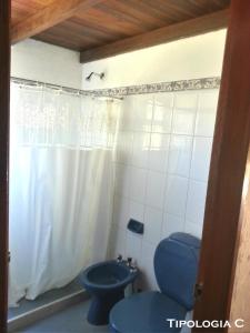 a bathroom with a blue toilet and a shower curtain at Cabañas La Paloma in La Paloma