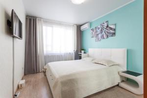 a bedroom with a white bed and a blue wall at Колибри#1 у Площади Победы-Черняховского Центр in Kaliningrad