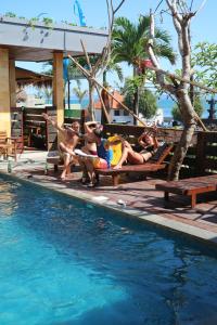 a group of people sitting on a bench next to a swimming pool at Bima Sakti Homestay Echo Beach Canggu in Canggu