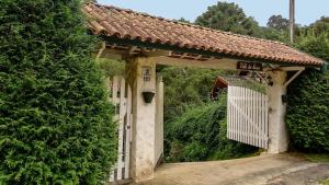 una entrada a una casa con una puerta y un seto en Suíte "Vale do Luar" - Capivari, en Campos do Jordão