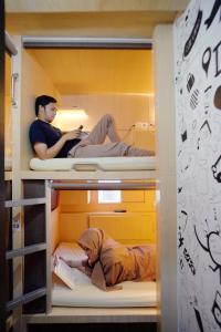 two people sitting on bunk beds in a room at INAP at Capsule Hostel in Bandung