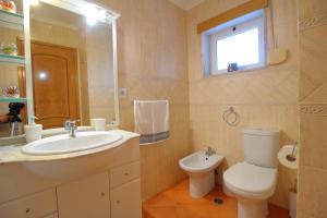 a bathroom with a sink and a toilet and a window at Condominio do Mar in Lagos