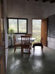 uma sala de jantar com mesa, cadeiras e janelas em La casa de la paz em Potrerillos