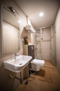 ein Bad mit einem Waschbecken, einer Dusche und einem WC in der Unterkunft Chola Serviced Apartment in Tiruchchirāppalli